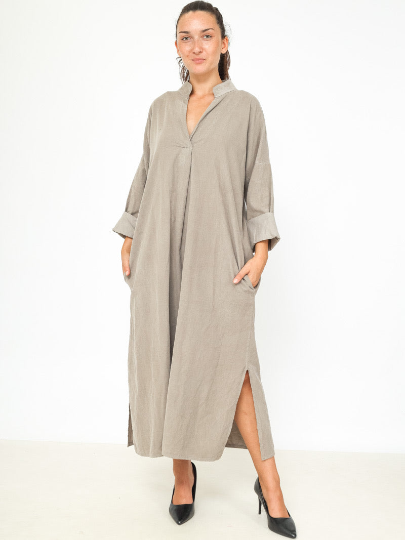 Woman wearing a long beige dress on a white background