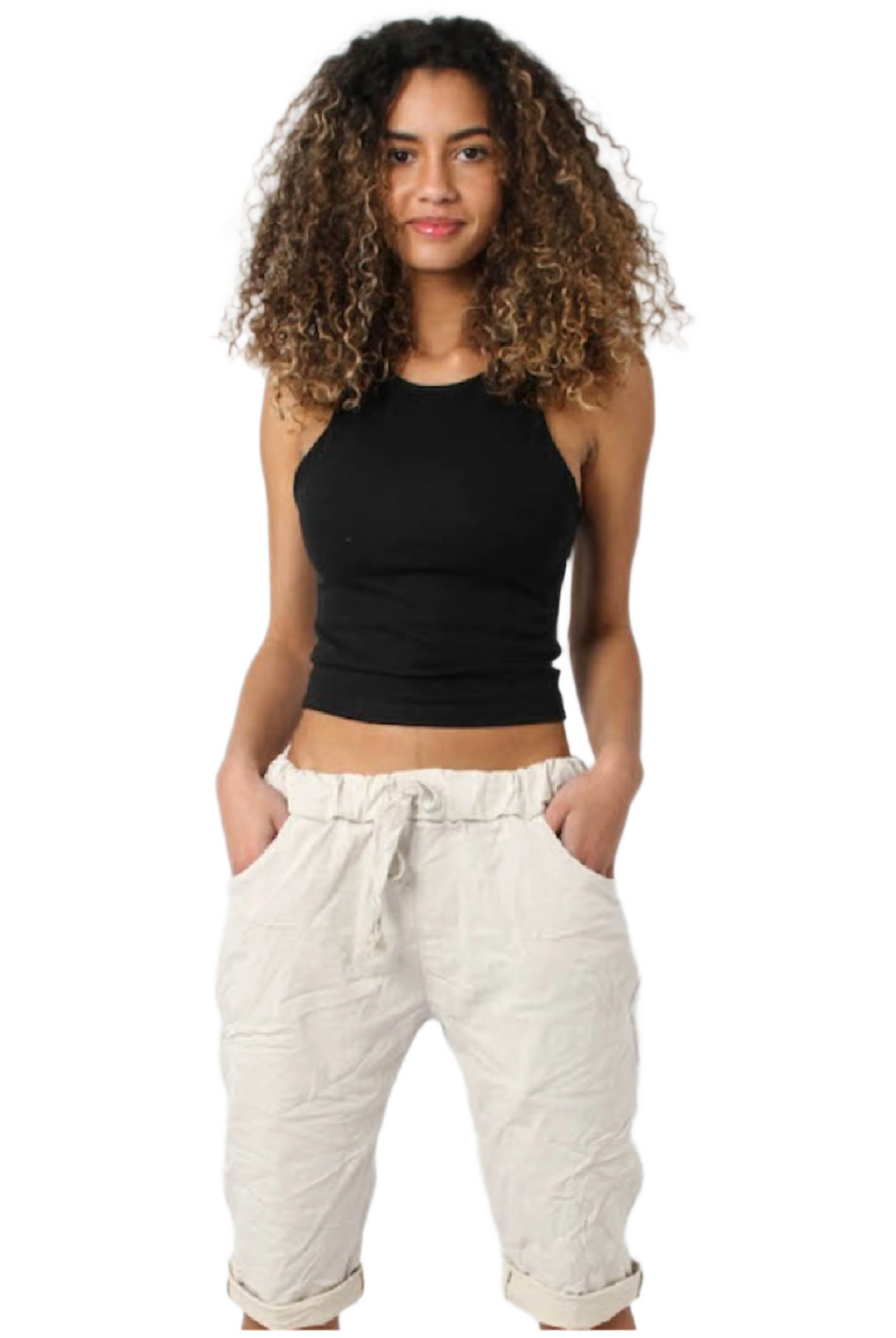 A woman standing, wearing beige Bermuda shorts with side pockets and a black sleeveless top.