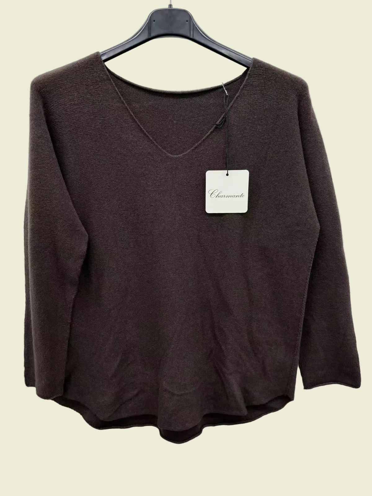 Brown sweater on a hanger with a visible brand tag against a white background
