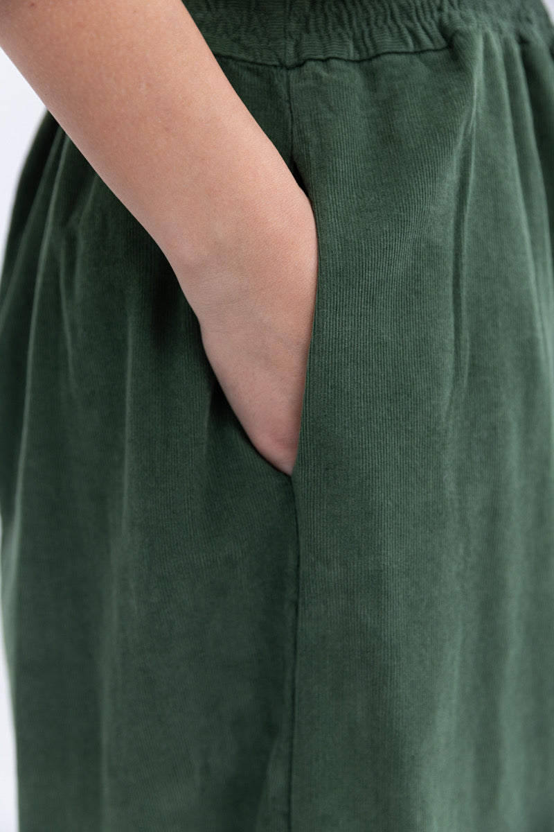 Green pants with a hand in a pocket on a plain background