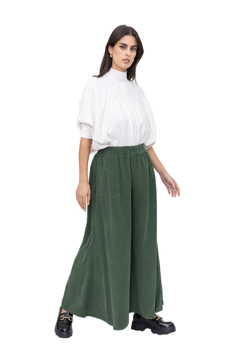 Woman wearing a white blouse and green wide-leg pants on a white background