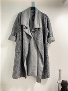 Gray coat hanging on a rack against a white wall