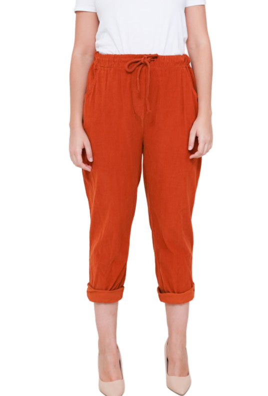 Woman wearing a white t-shirt and orange pants on a white background