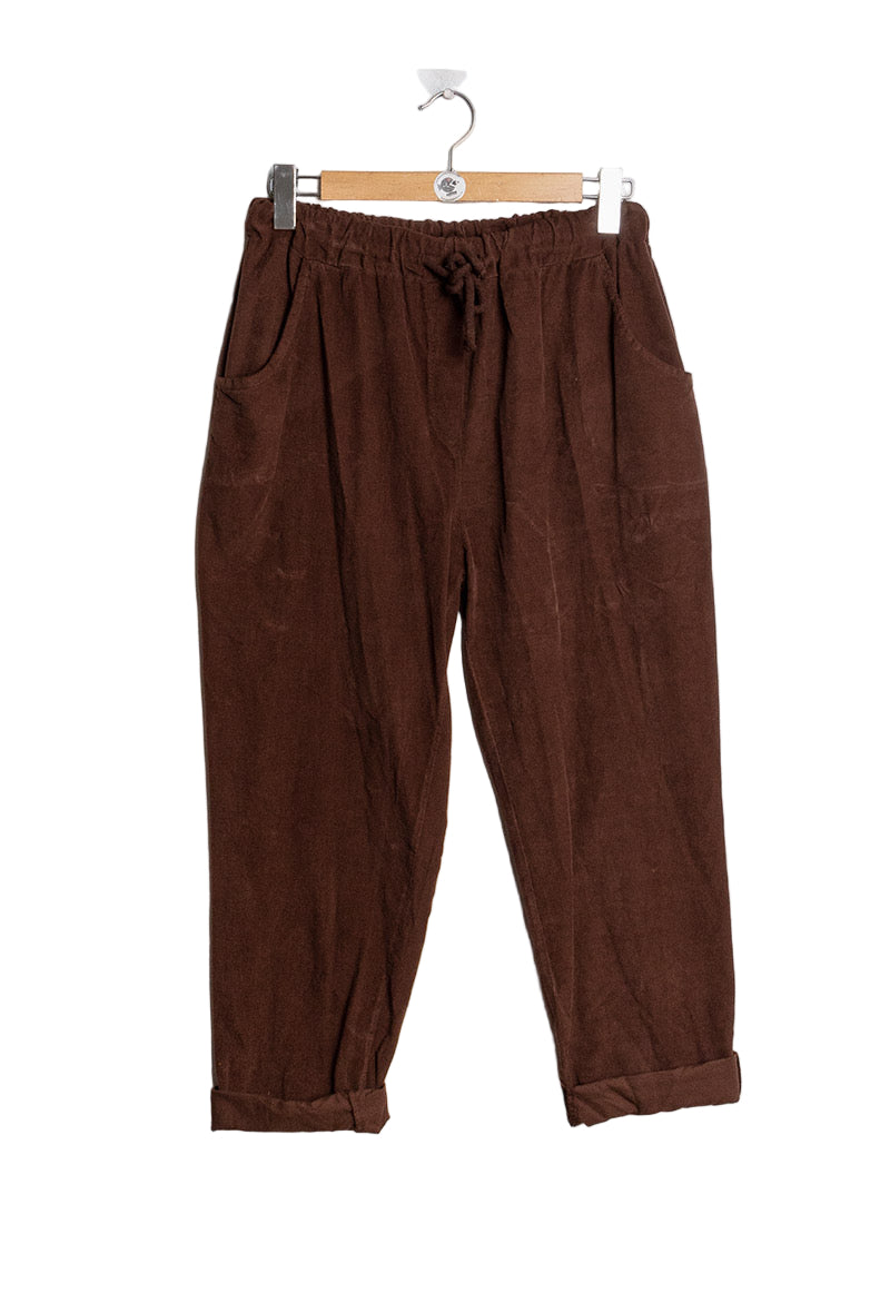 Brown pants hanging on a wooden hanger against a white background