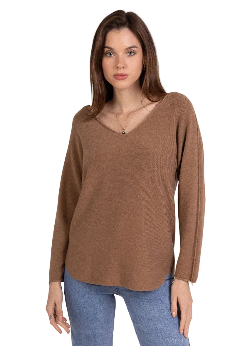 Woman wearing a brown long-sleeve top and blue jeans on a plain background