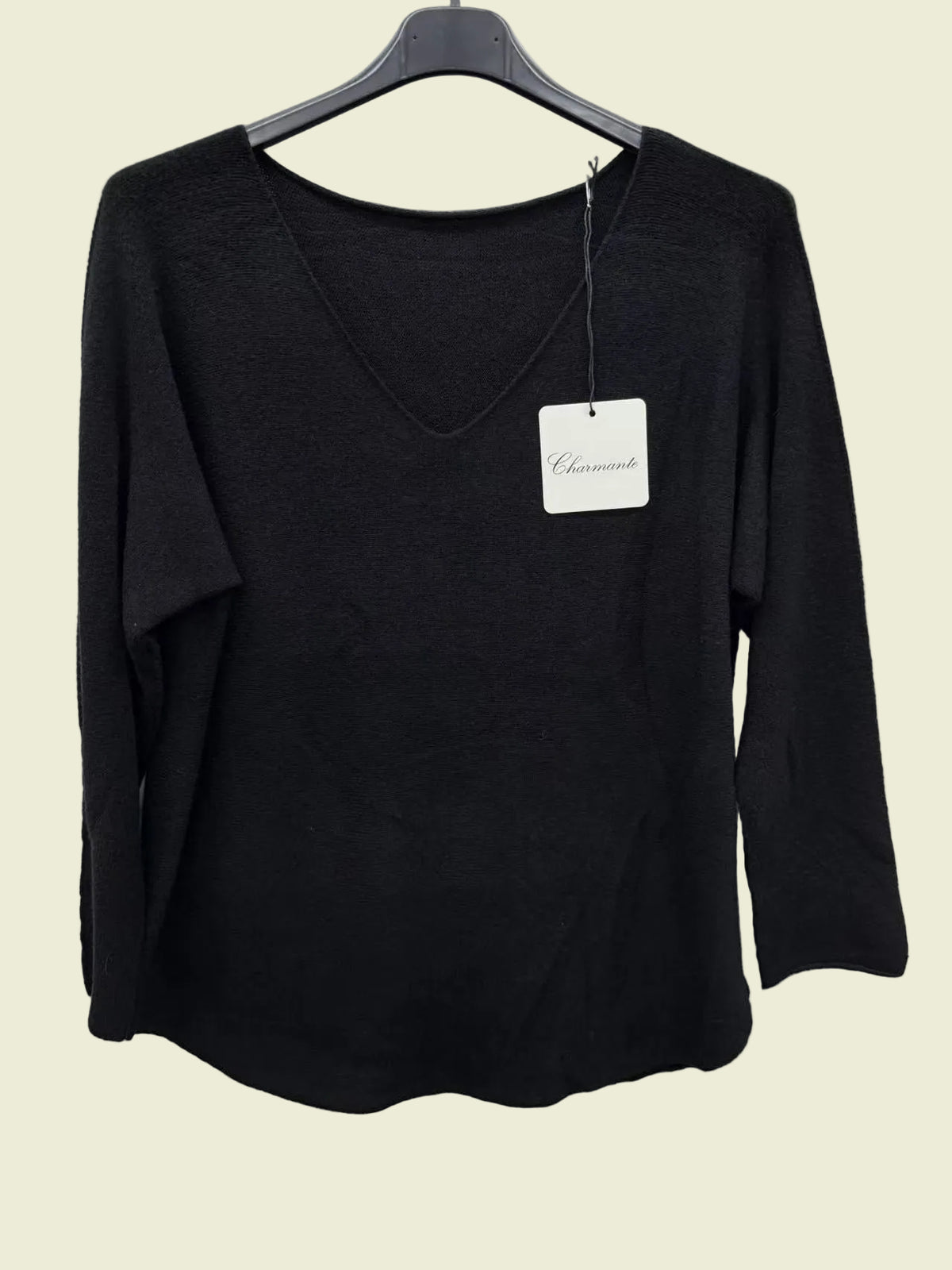 Black long-sleeve top on a hanger with a visible brand tag against a white background