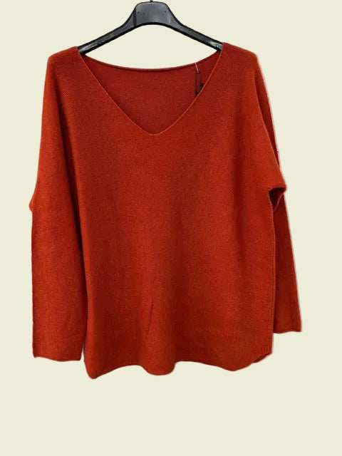 Orange sweater on a black hanger against a white background