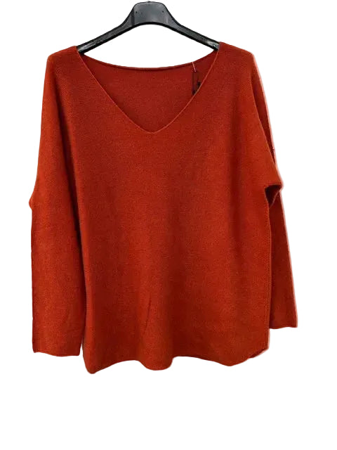 Orange sweater on a black hanger against a white background
