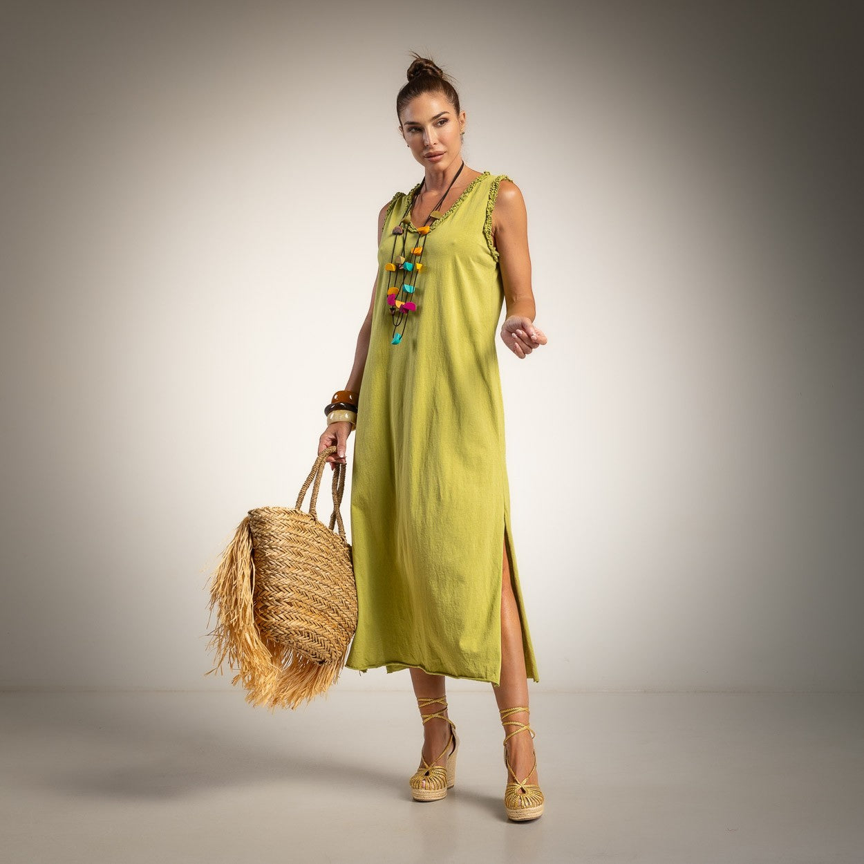 A woman modeling a sleeveless lime green midi dress wit side slits