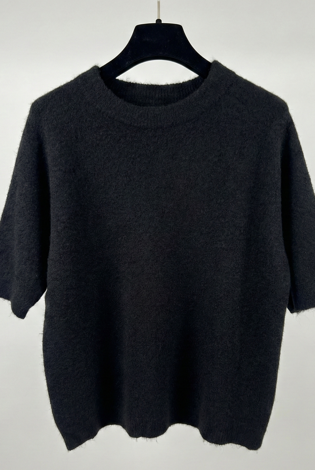 Black sweater on a hanger against a white background