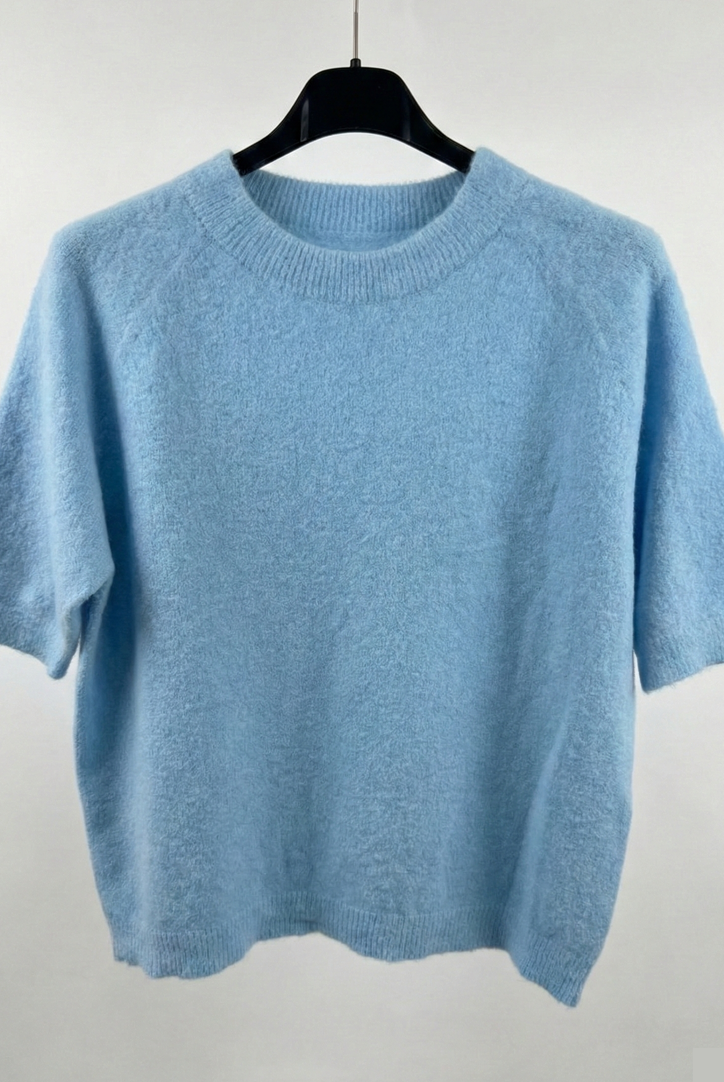 Light blue sweater on a hanger against a white background