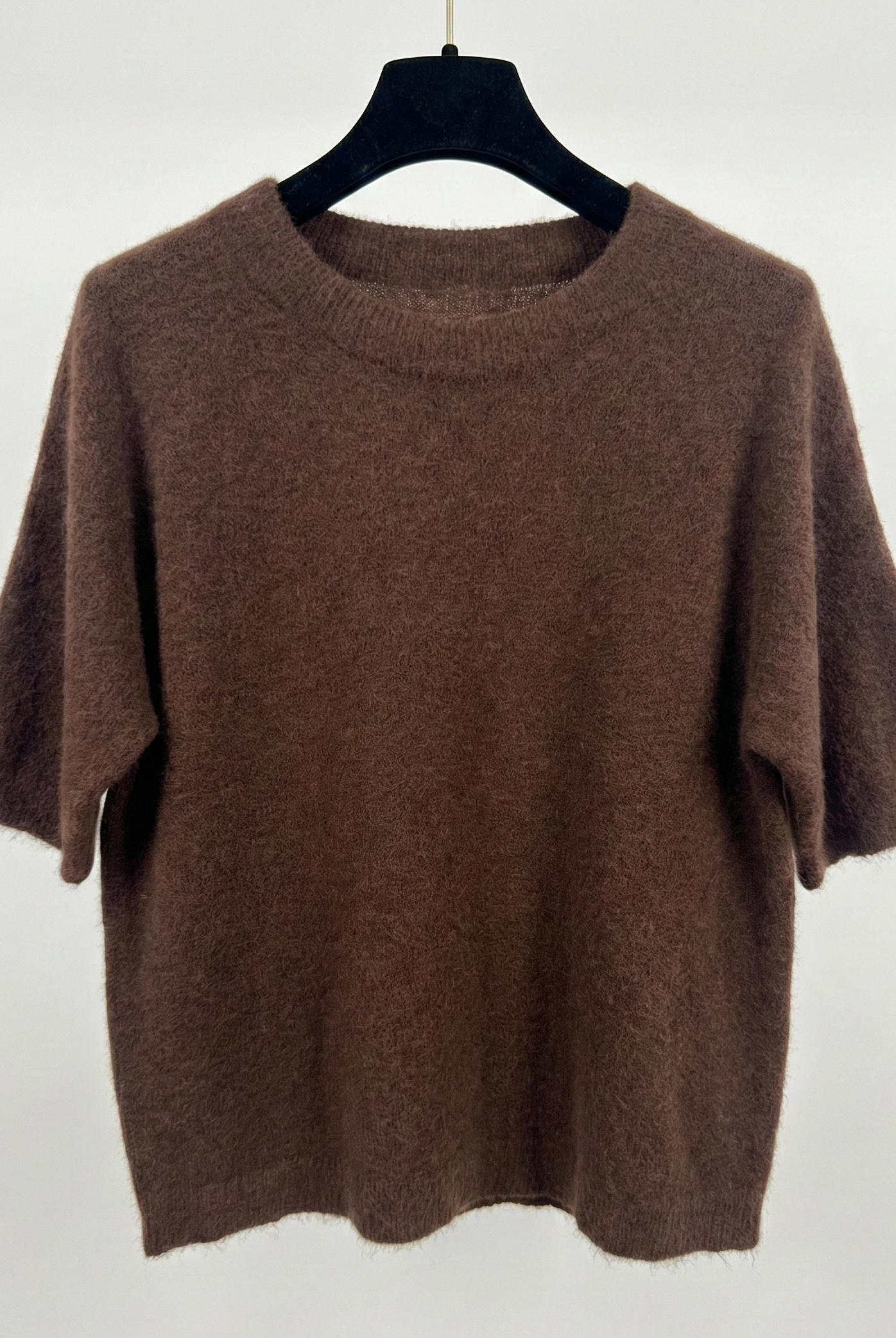 Brown sweater on a hanger against a white background