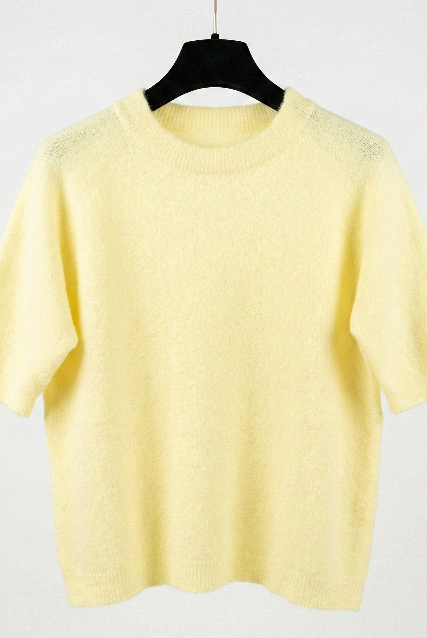 Yellow sweater on a hanger against a white background