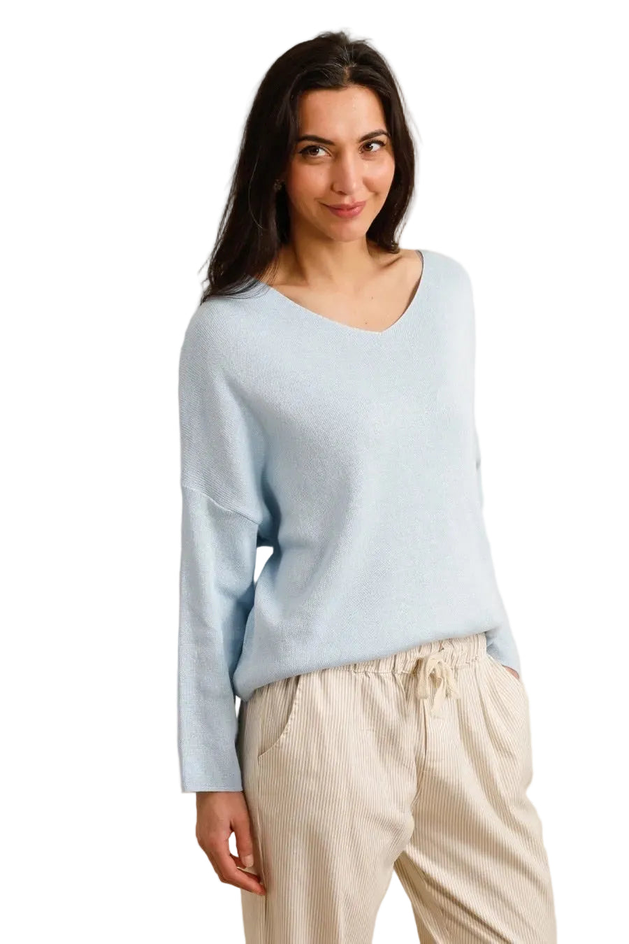 Woman wearing a light blue sweater and beige pants against a beige background