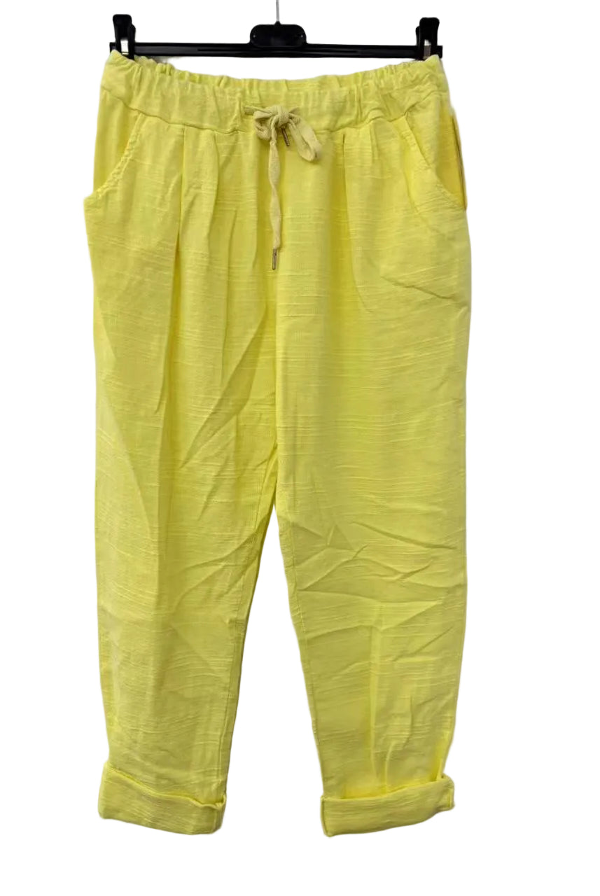 Yellow pants with a drawstring on a hanger against a white background