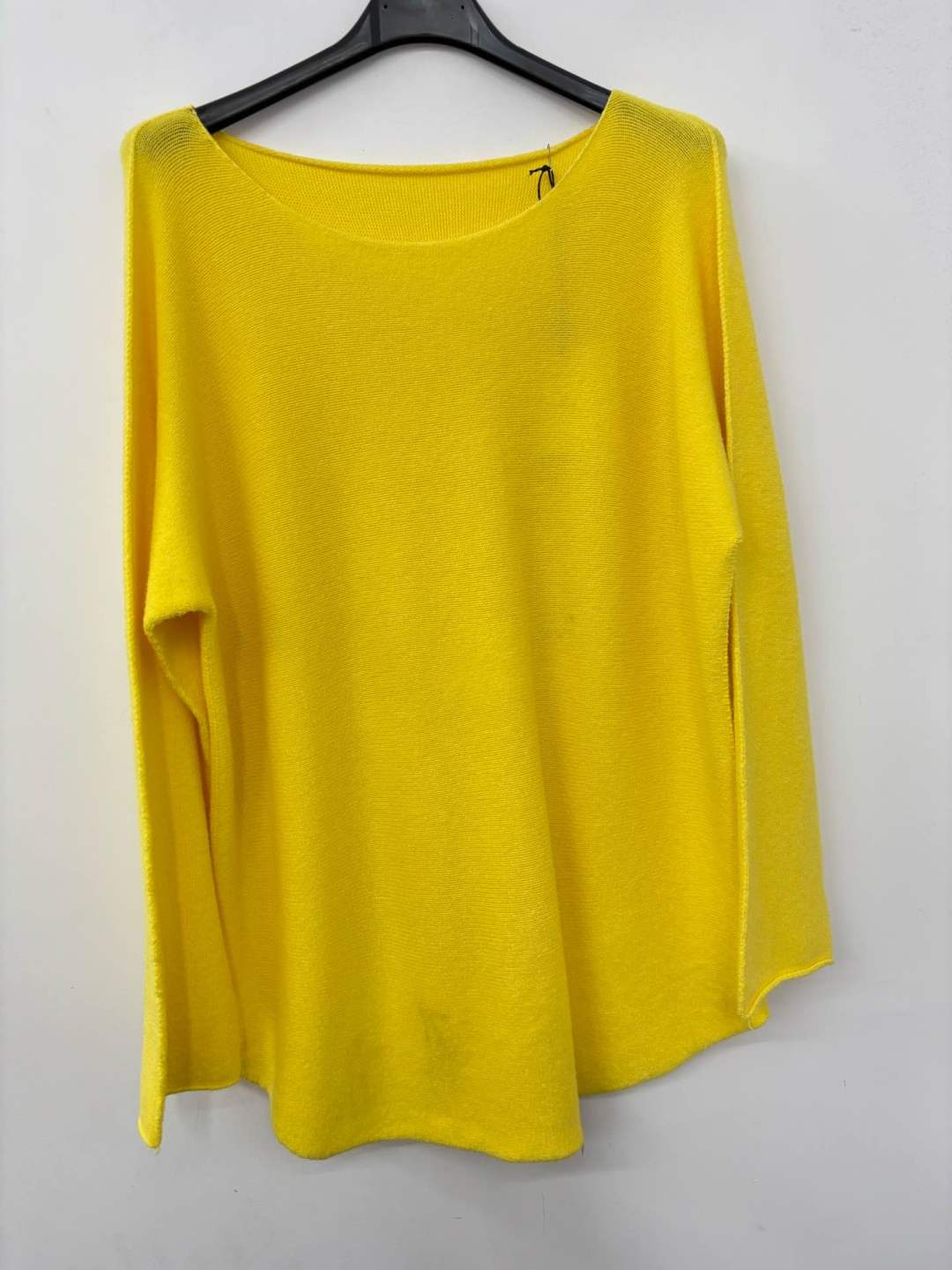 Yellow top on a hanger against a white background