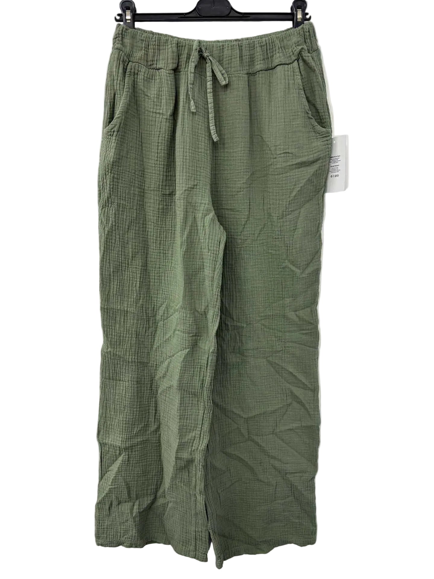 Green cotton gauze pants on a hanger against a white background