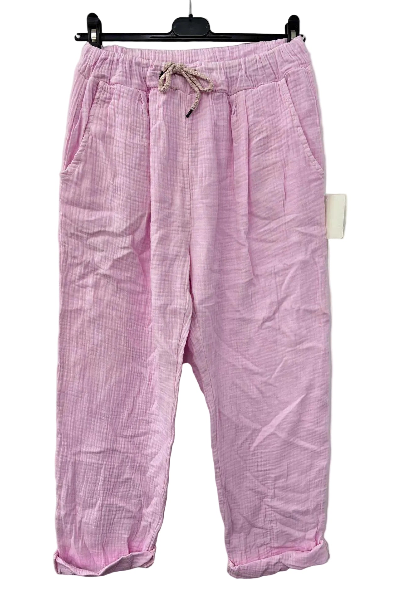 Pink cotton gauze trousers on a hanger against a white background