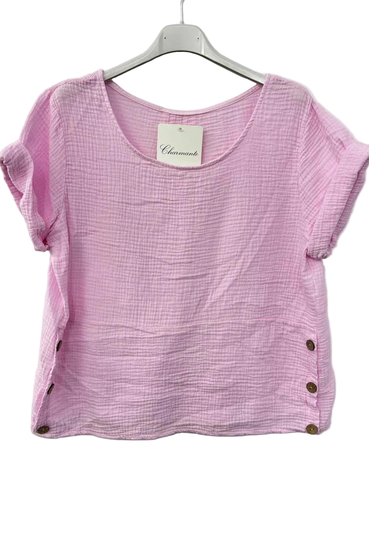 Pink cotton gauze top with buttons on a hanger against a white background