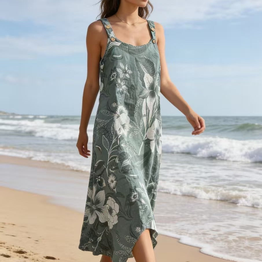 Woman in a green floral dress walking on a beach with ocean waves in the background