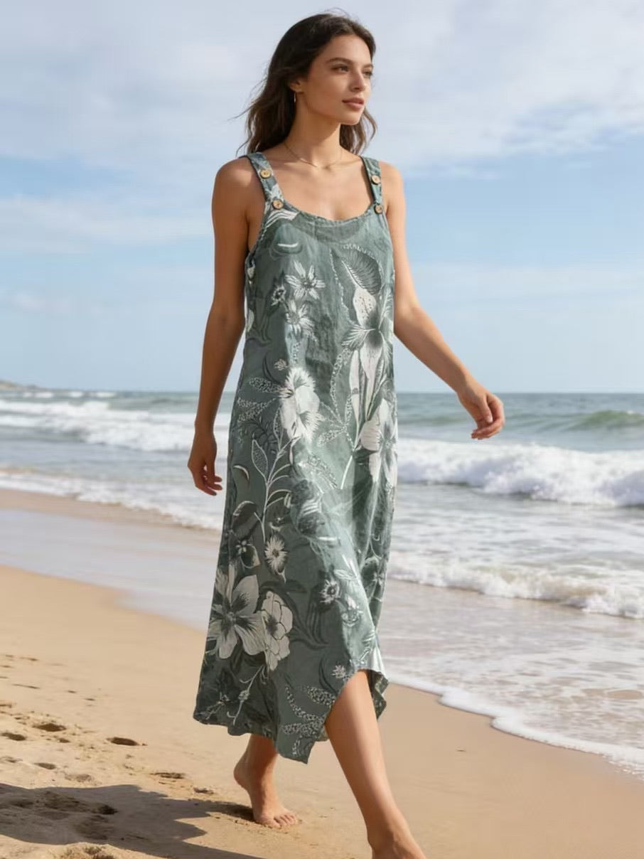 Woman in a green floral dress walking on a beach with ocean waves in the background