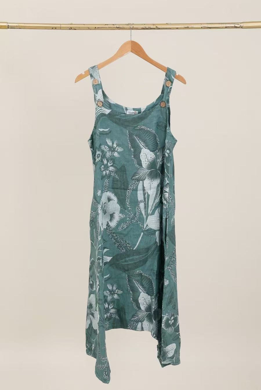 Green floral dress hanging on a wooden hanger against a beige background