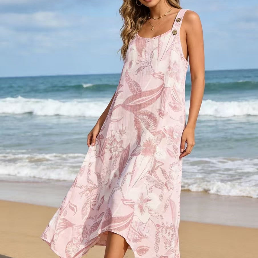 Woman in a pink floral dress standing on a beach with ocean waves in the background