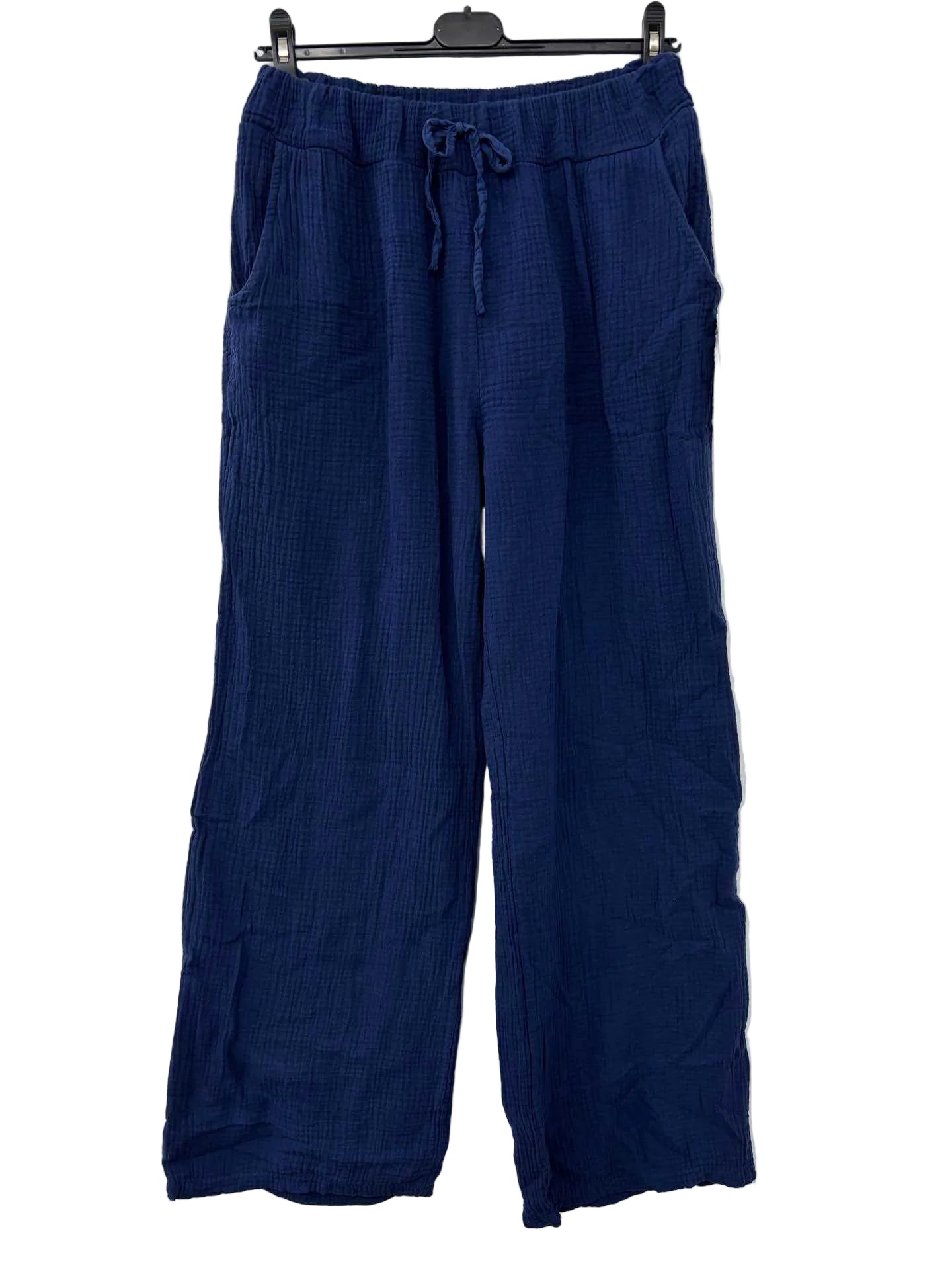 Navy blue pants hanging on a rack against a white wall