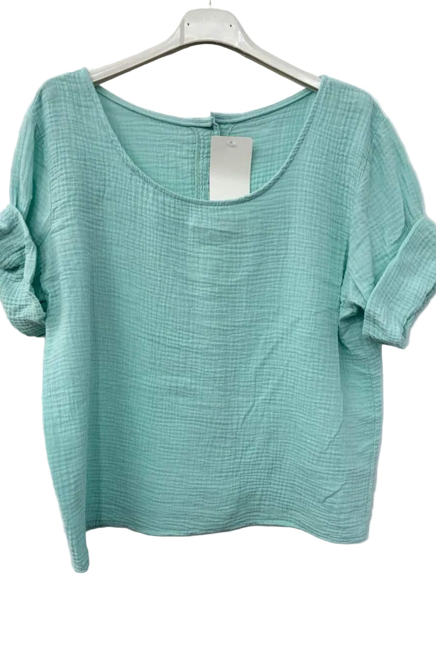 Turquoise textured top on a hanger against a white background