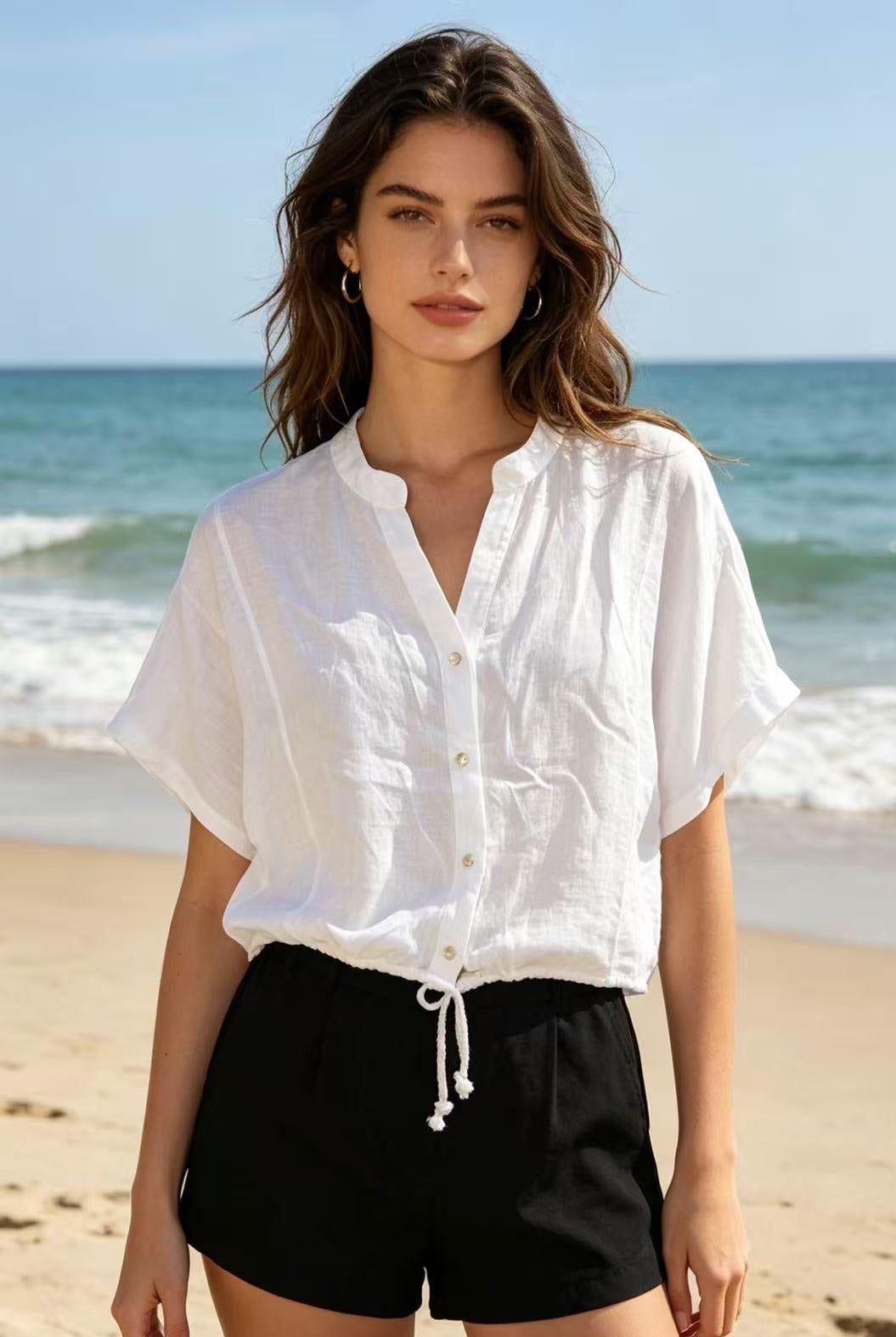 Woman wearing a white shirt and black shorts on a beach