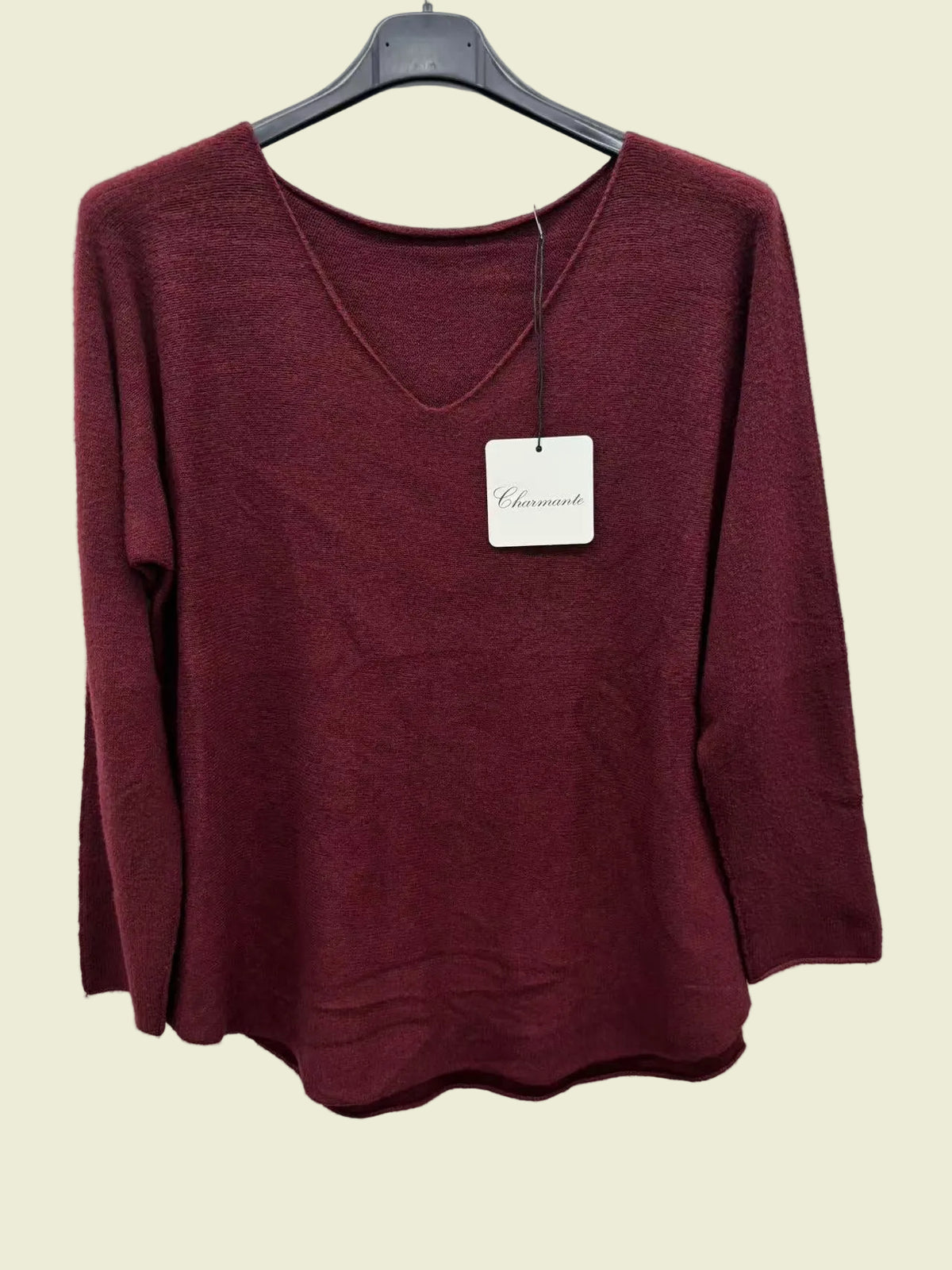 A women's long-sleeve knit sweater in a deep burgundy or maroon color, hanging on a black hanger against a plain white background.