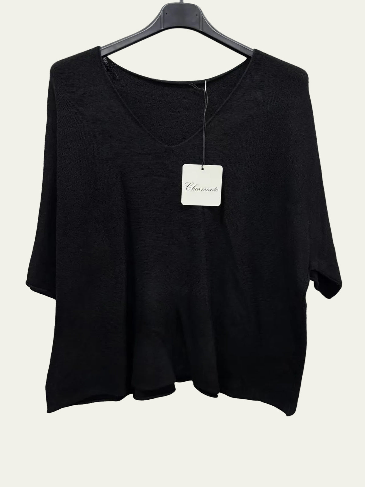 A black women's knit top with a wide scoop neckline and elbow-length sleeves, hanging on a black hanger