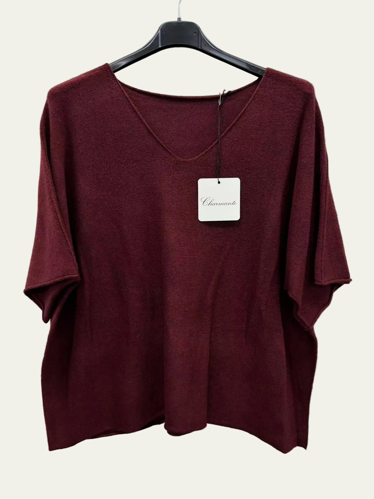 A burgundy short-sleeve V-neck top hanging on a black hanger
