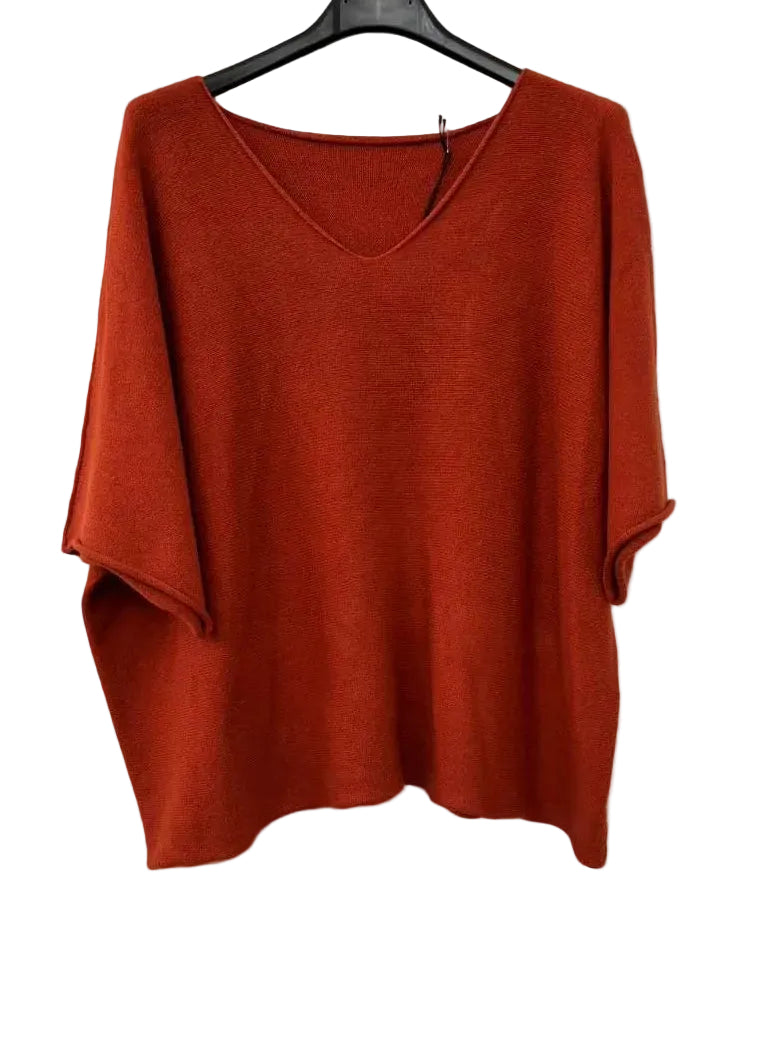 A burnt orange knit sweater with a v neckline and elbow-length sleeves
