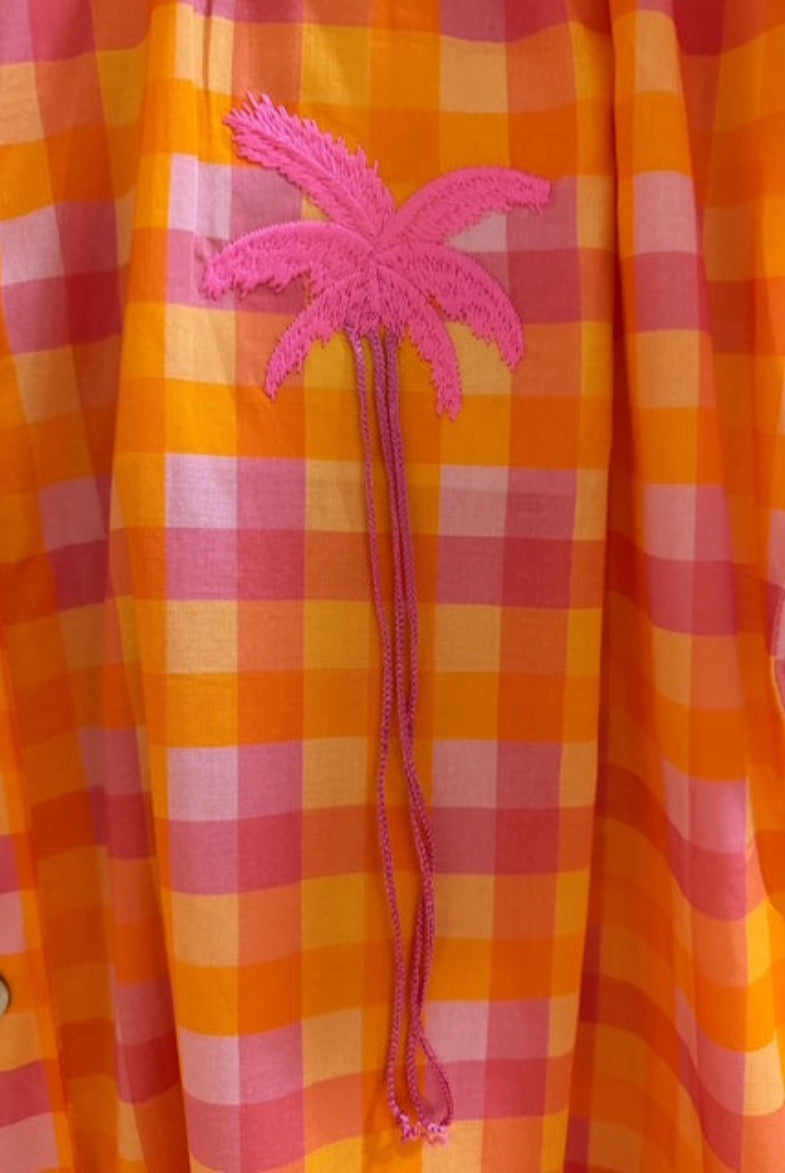 Orange and pink checkered shirt with a pink palm tree design on a blurred background