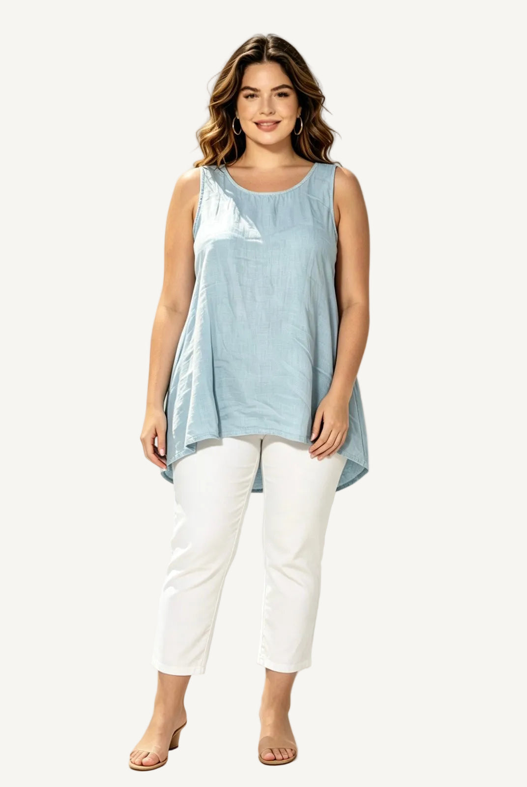 Woman wearing a light blue sleeveless top and white pants against a white background with palm leaves.