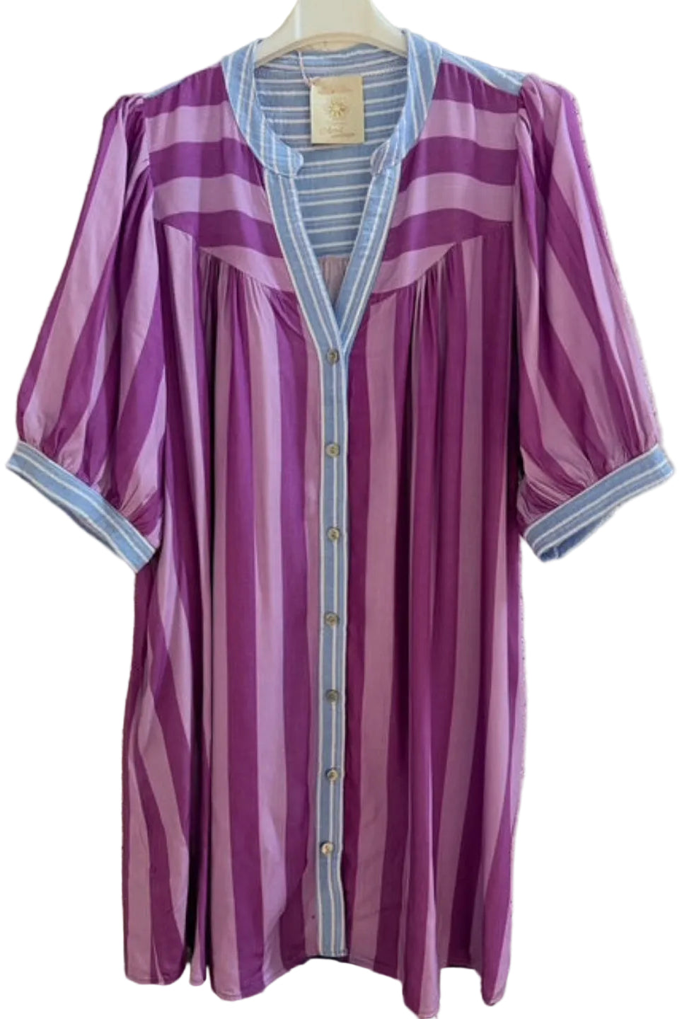 Purple striped dress with blue trim on a hanger against a textured wall.