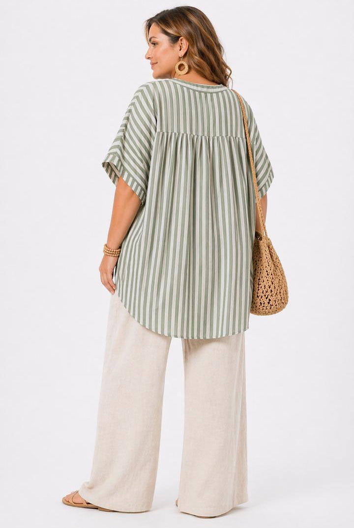 Woman wearing a green and white striped shirt with wide-leg pants on a white background