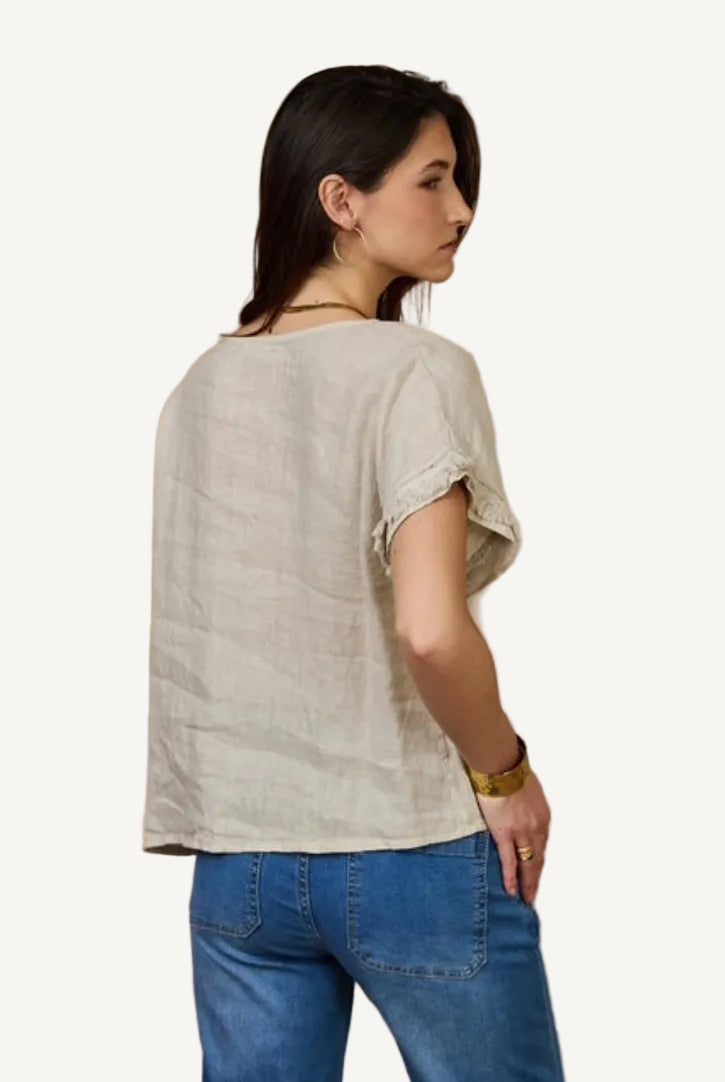 Woman wearing a beige top and blue jeans against a beige background