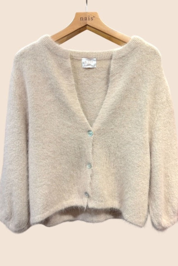 A soft knit cardigan sweater in beige, hanging on a wooden hanger - the cardigan features a V-neck, long sleeves, and a front button closure with light blue buttons.