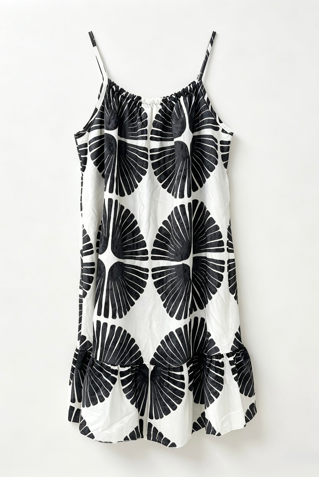 A white slip dress with thin spaghetti straps and a bold black geometric fan pattern