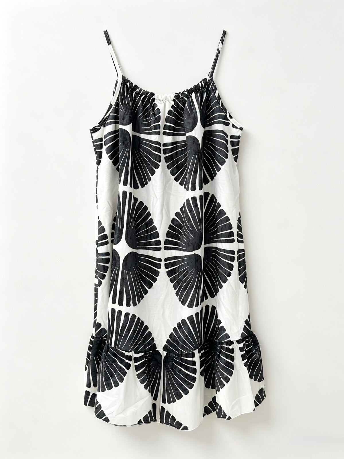 A white slip dress with thin spaghetti straps and a bold black geometric fan pattern