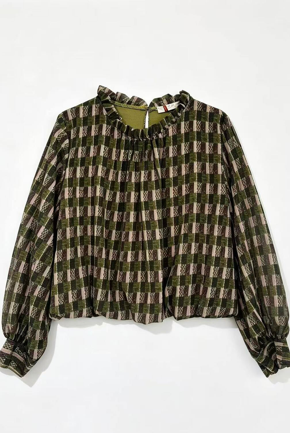 A long-sleeve blouse with a green, brown, and beige plaid pattern, featuring a ruffled high neckline and gathered cuffs, laid flat against a white background.