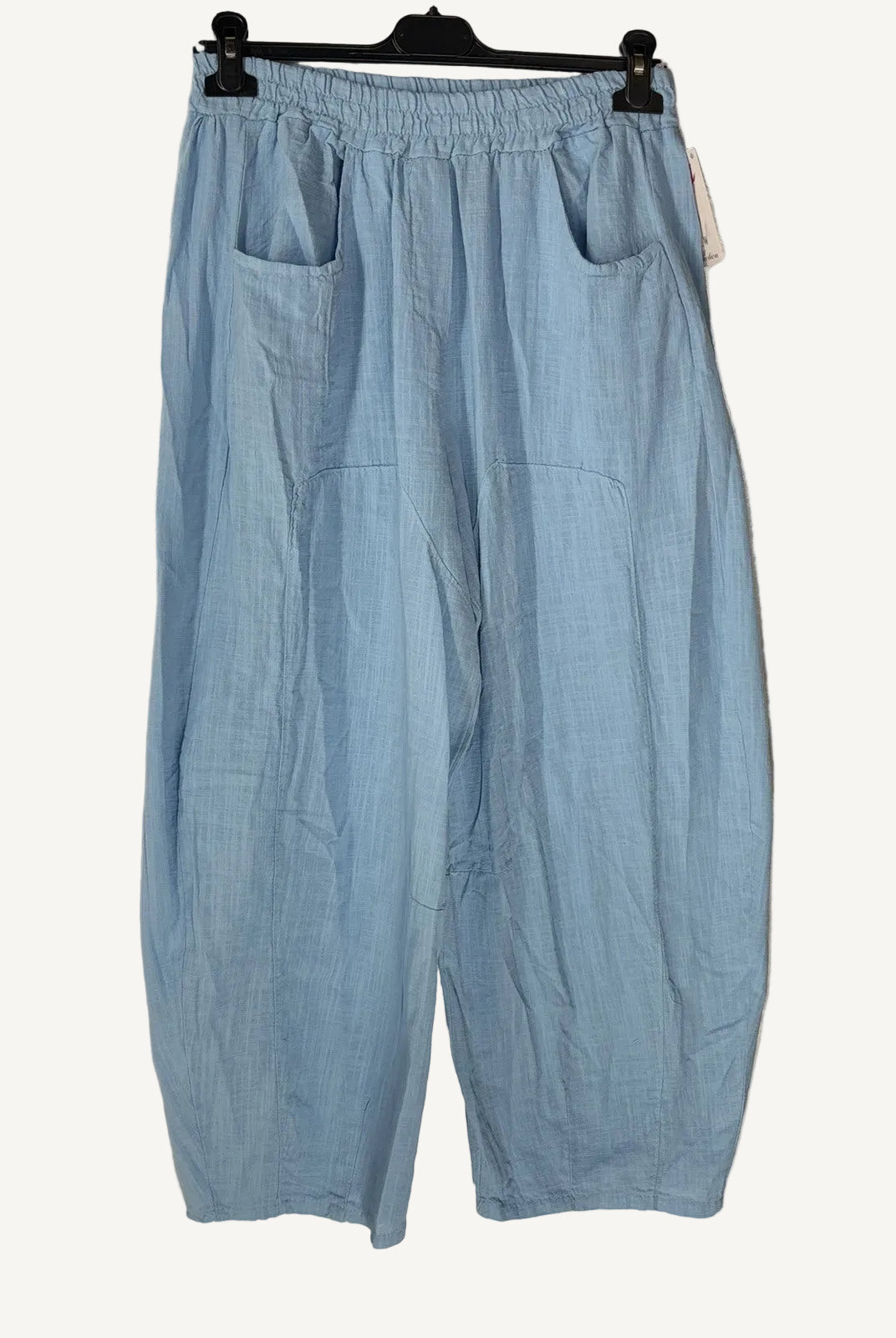 Light blue pants hanging on a hanger against a neutral background