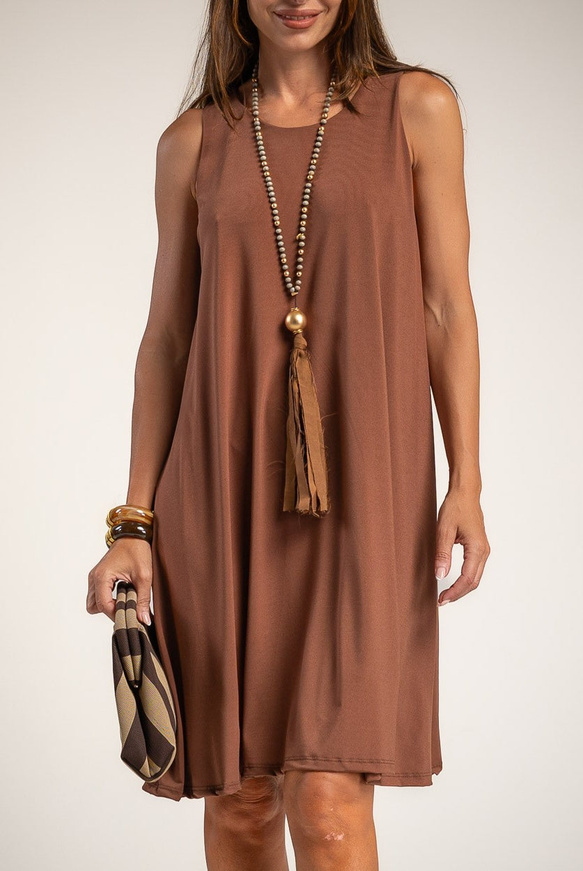 A woman wearing a sleeveless, knee-length brown dress with a relaxed A-line silhouette