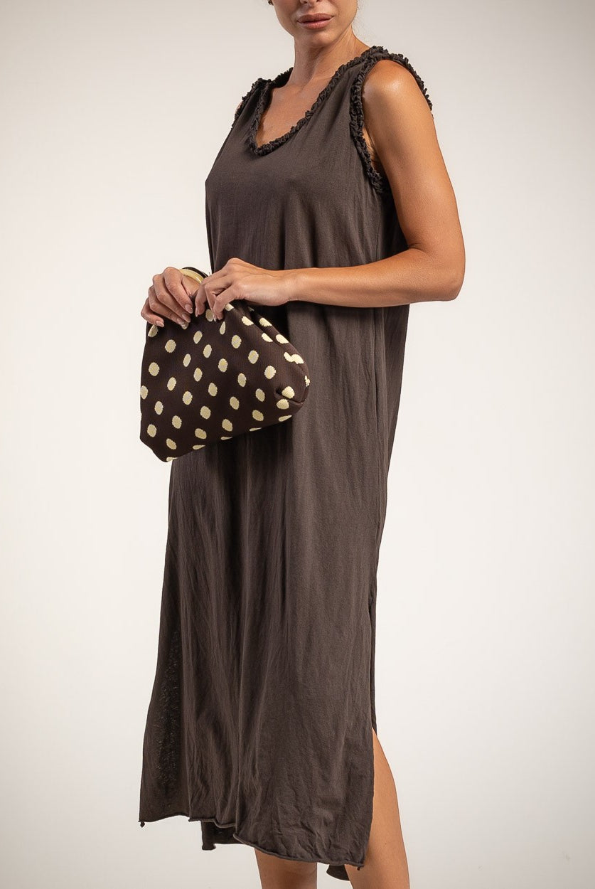 A woman wearing a sleeveless brown midi dress with side slits