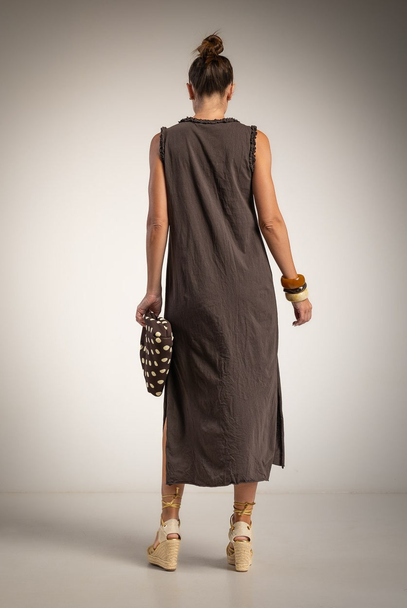 A woman is shown from behind wearing a sleeveless, dark brown linen midi dress with side slits