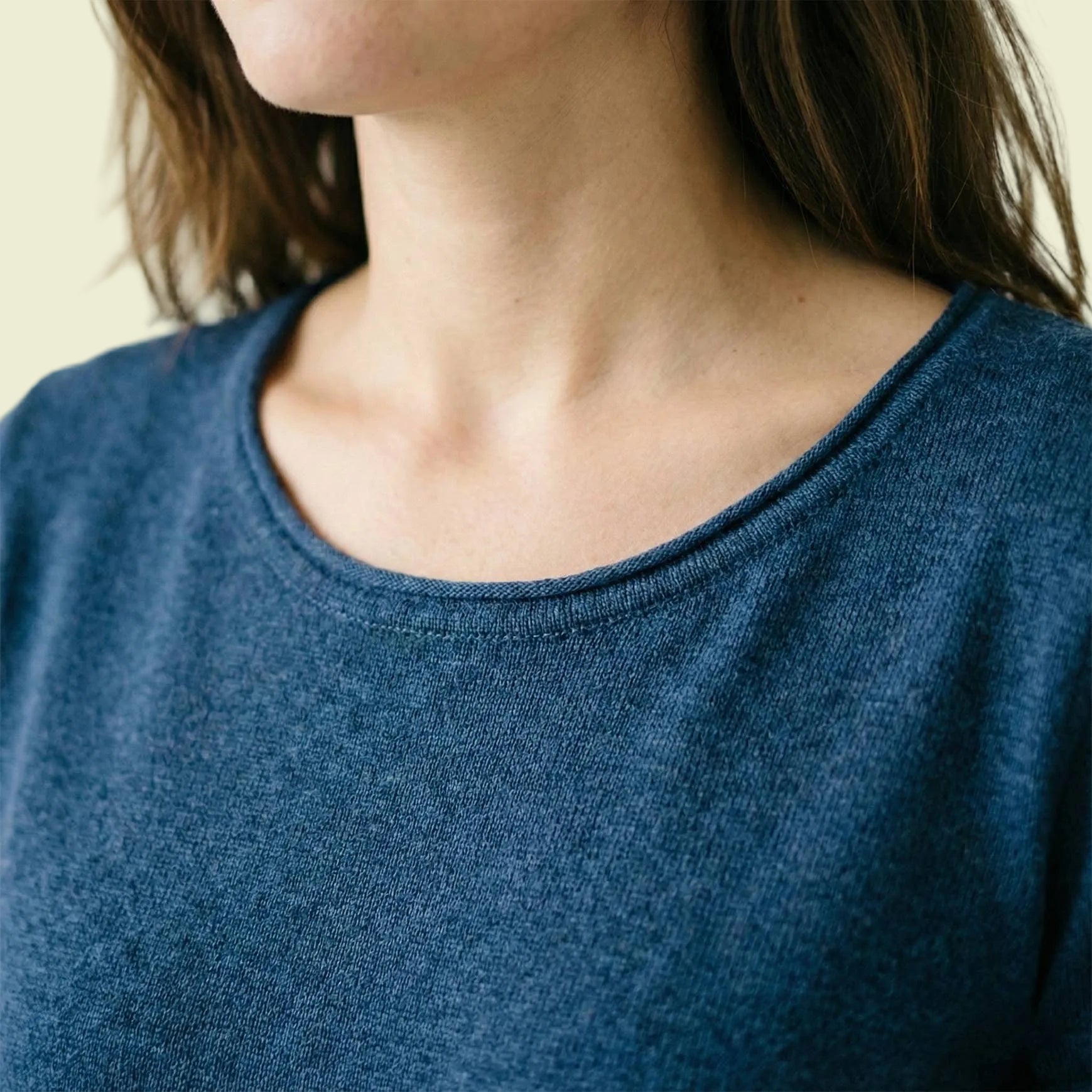 Close-up of a person wearing a blue sweater with a neutral background
