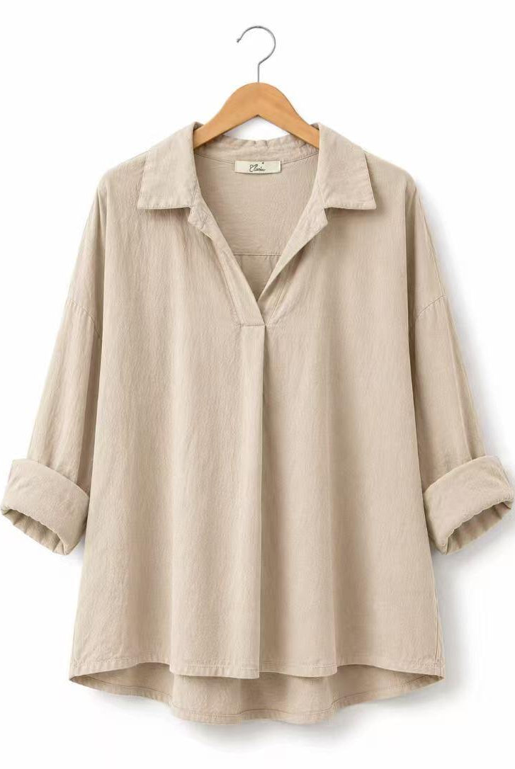 A beige long-sleeve linen shirt with a collar and rolled cuffs, hanging on a wooden hanger against a white background.