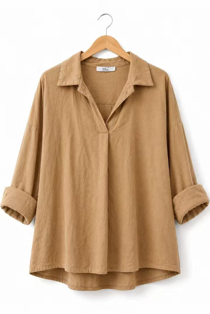 A tan long-sleeve linen shirt with a collar and rolled cuffs, hanging on a wooden hanger against a white background.